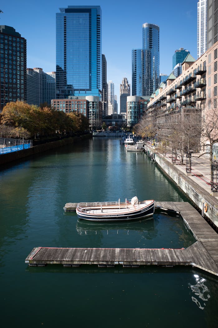 A tranquil view of the Chicago River with a boat and urban skyscrapers in the backdrop.